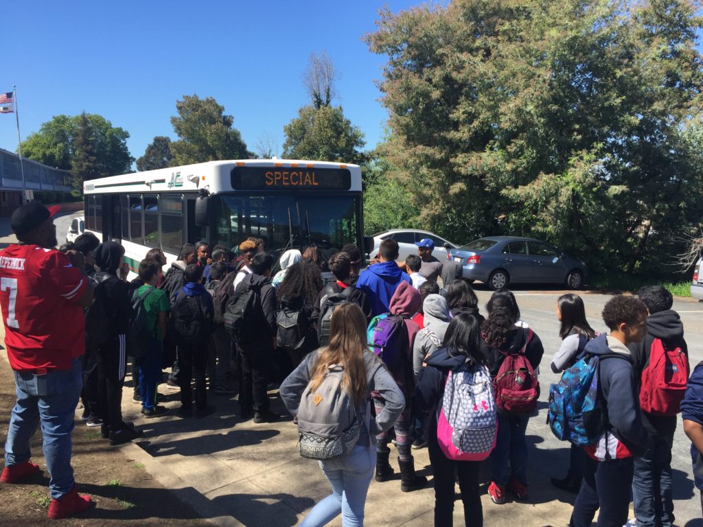 An image of a group of students waiting for a bus. 