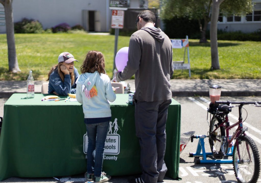An image of a father and daughter learning about Safe Routes to School at an outreach table.
